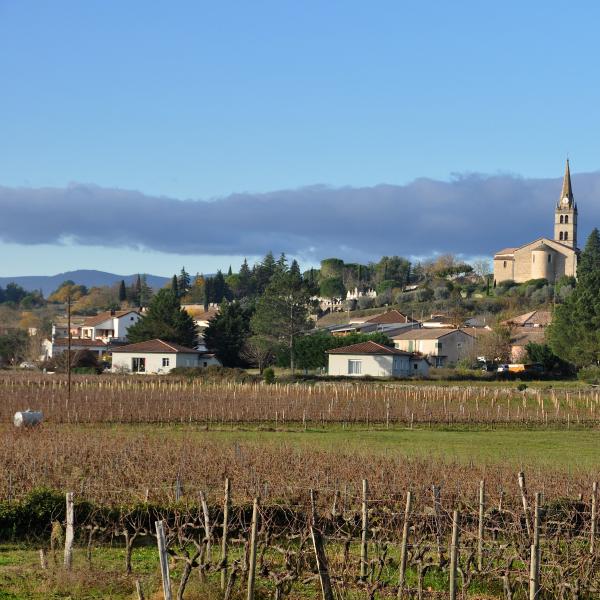 Vue de Lablachère en Ardèche, avec son église sur les hauteurs et les vignes au premier plan.
