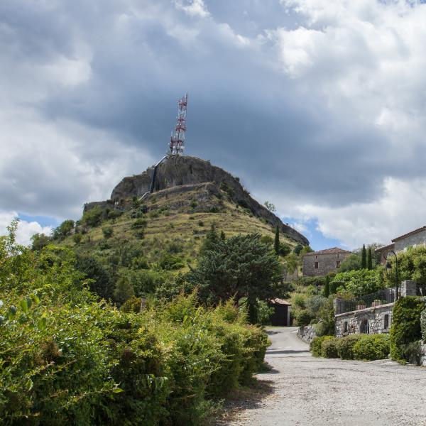 Village pittoresque de Sampzon en Ardèche : église en pierre et colline verdoyante.