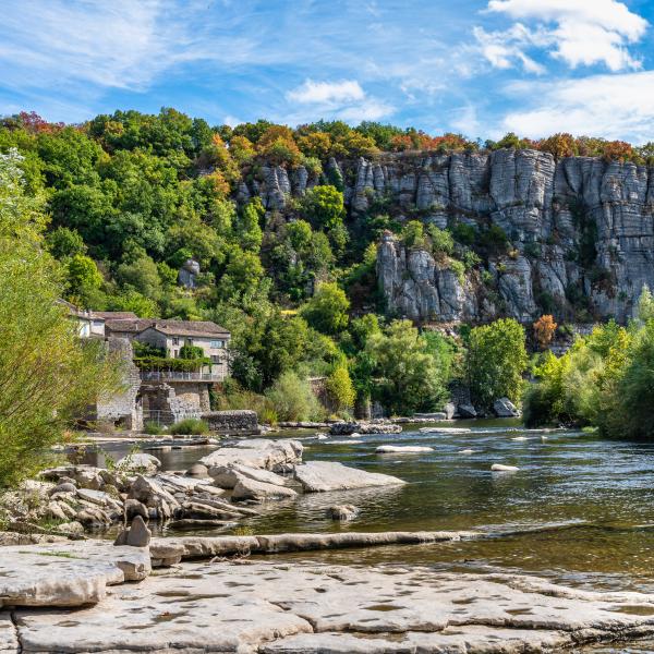 Village pittoresque de Vogüé en Ardèche : maisons en pierre, rivière et falaises boisées.