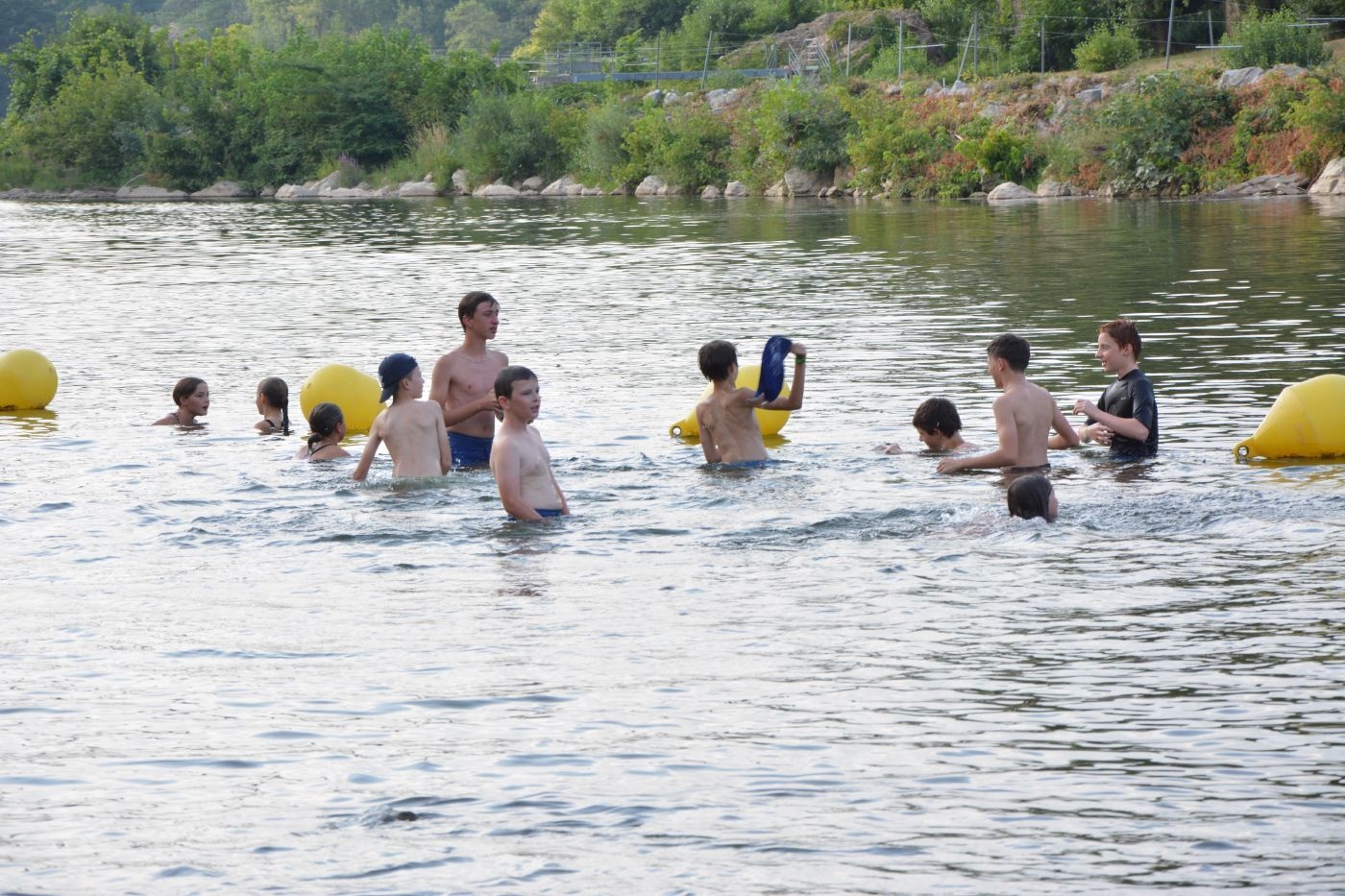 Groupe de personnes se baignant dans un lac avec bouées de délimitation jaunes